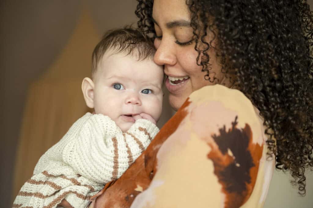 a tender moment as a mother cuddles her baby with affectionate joy.