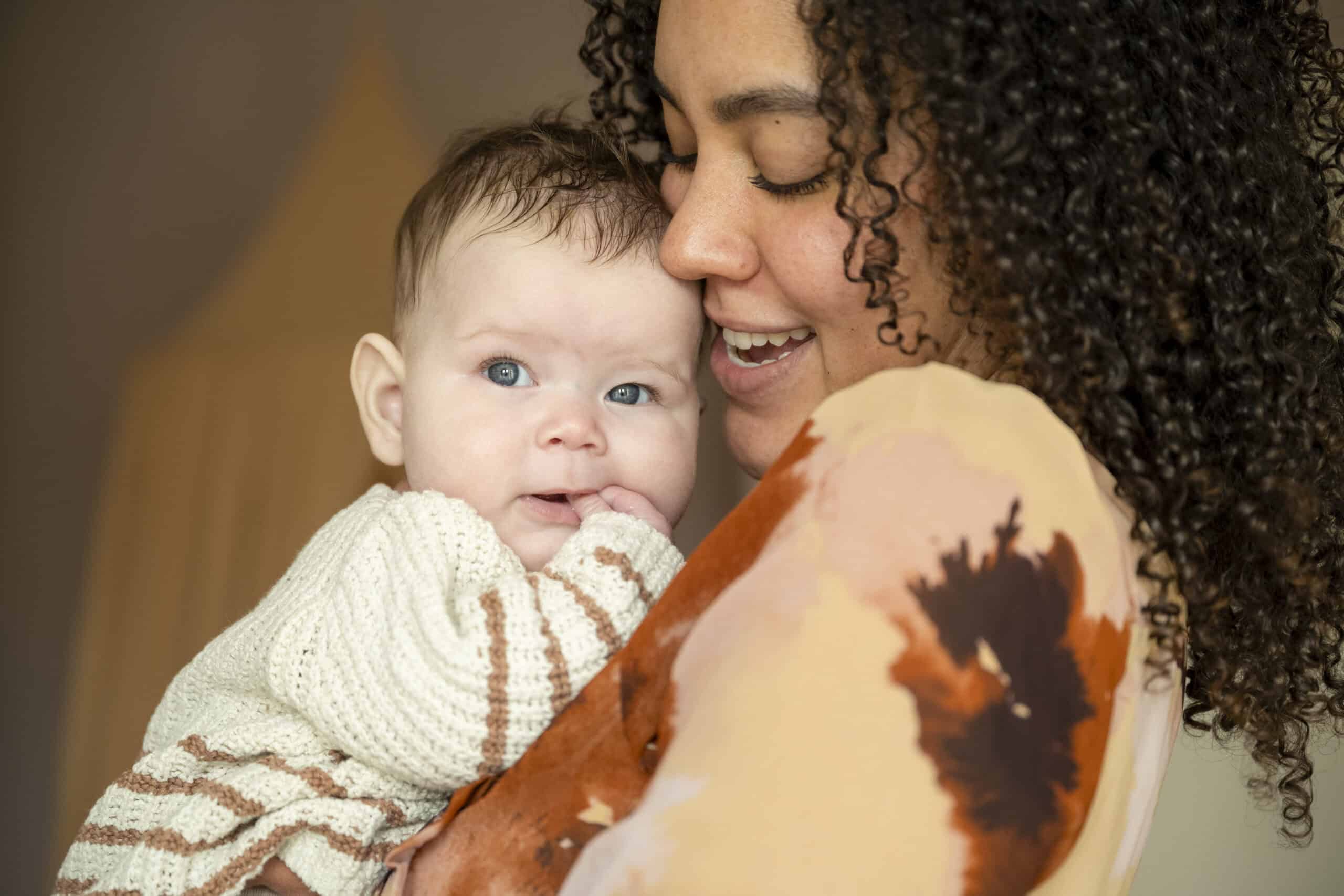 a tender moment as a mother cuddles her baby with affectionate joy.
